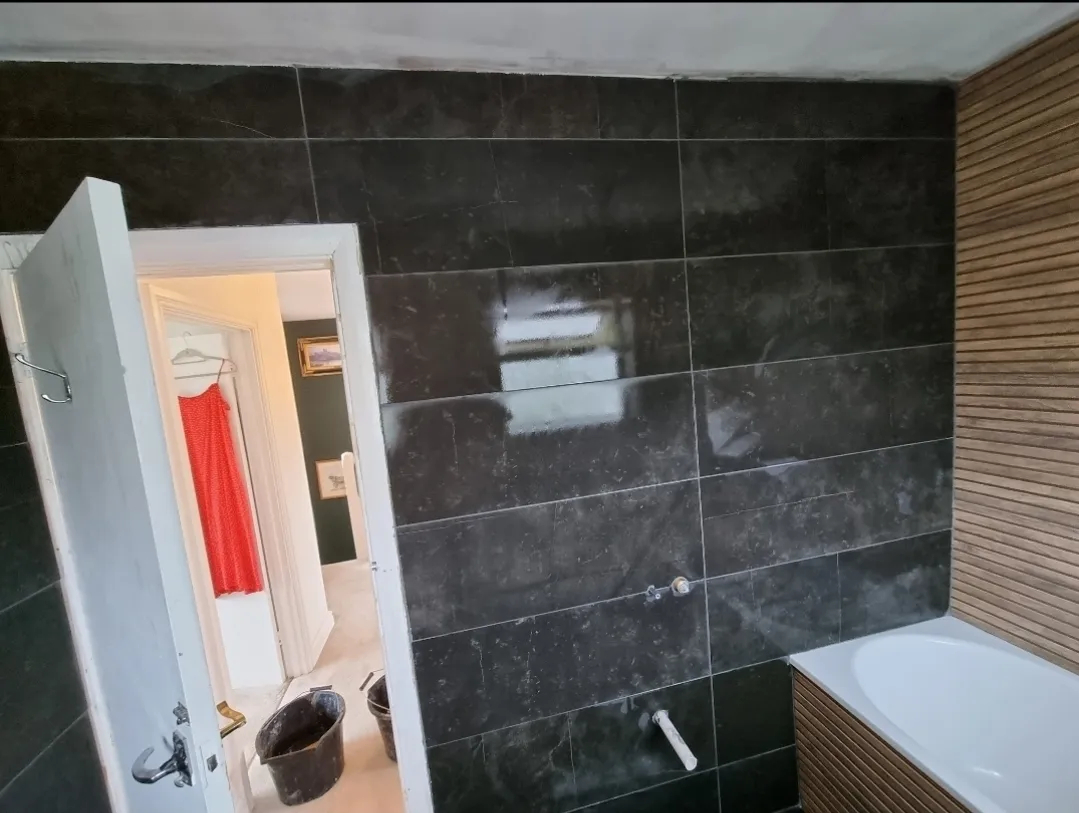 Bathroom black marble large tile with bath and timber slat panel in progress — bathroom renovation Surrey