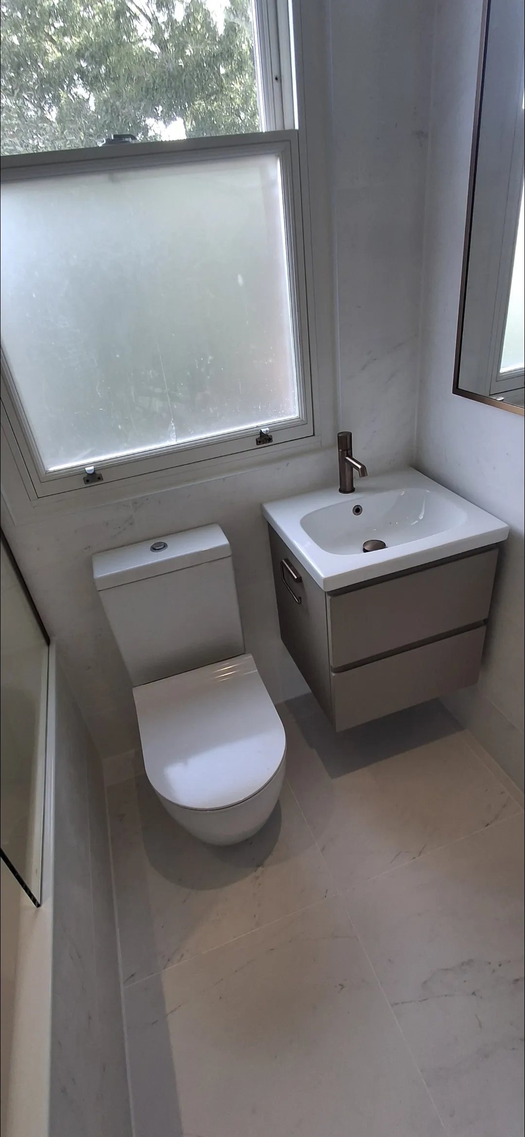 Bathroom with white marble tiles, floating vanity and bronze tap — bathroom renovation Surrey