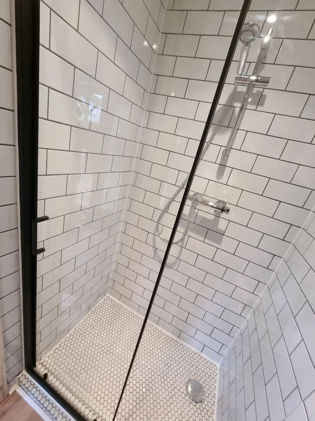 Bathroom white metro tile shower with hexagon floor tiles and black frame door — bathroom tilers Surrey