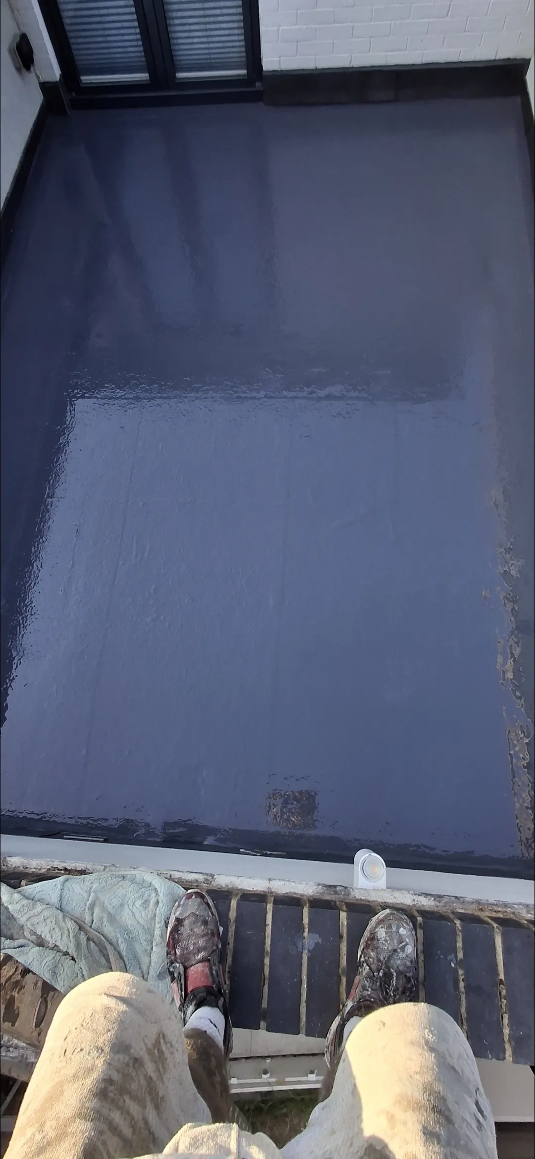 Dark GRP flat roof application in progress POV — flat roof contractors Surrey