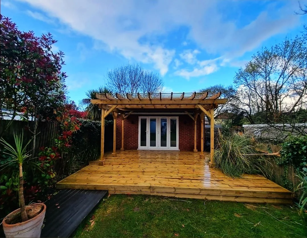 New timber decking and pergola installation with blue sky — garden builders Hampton SW London
