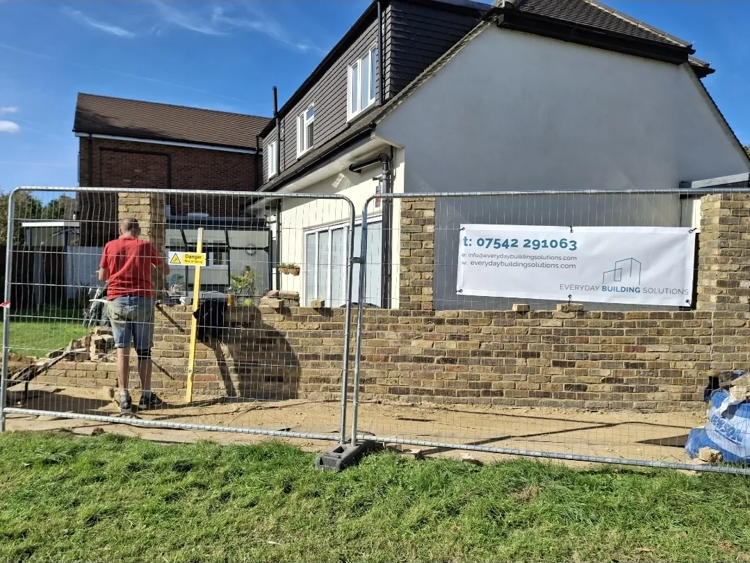 Everyday Building Solutions site hoarding with brickwork in progress — builders Surrey