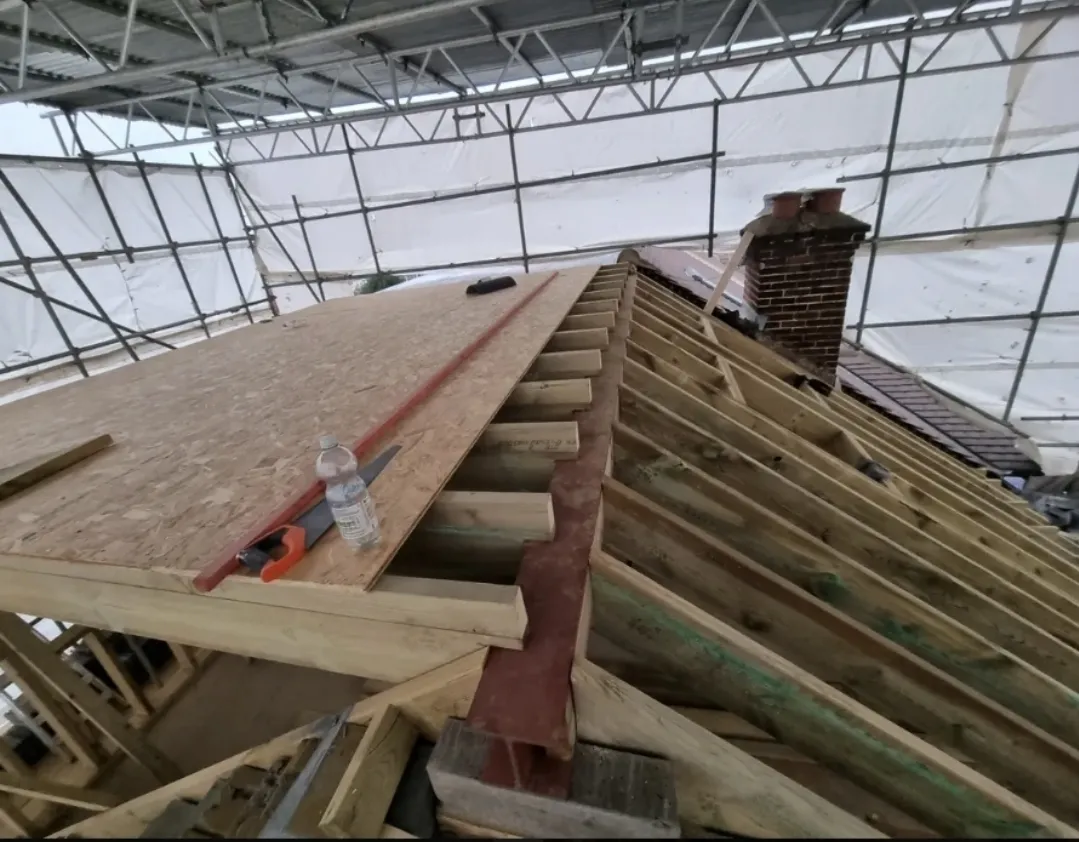 Roof structural work with new rafters and OSB boarding under scaffold tent — roofers Surrey